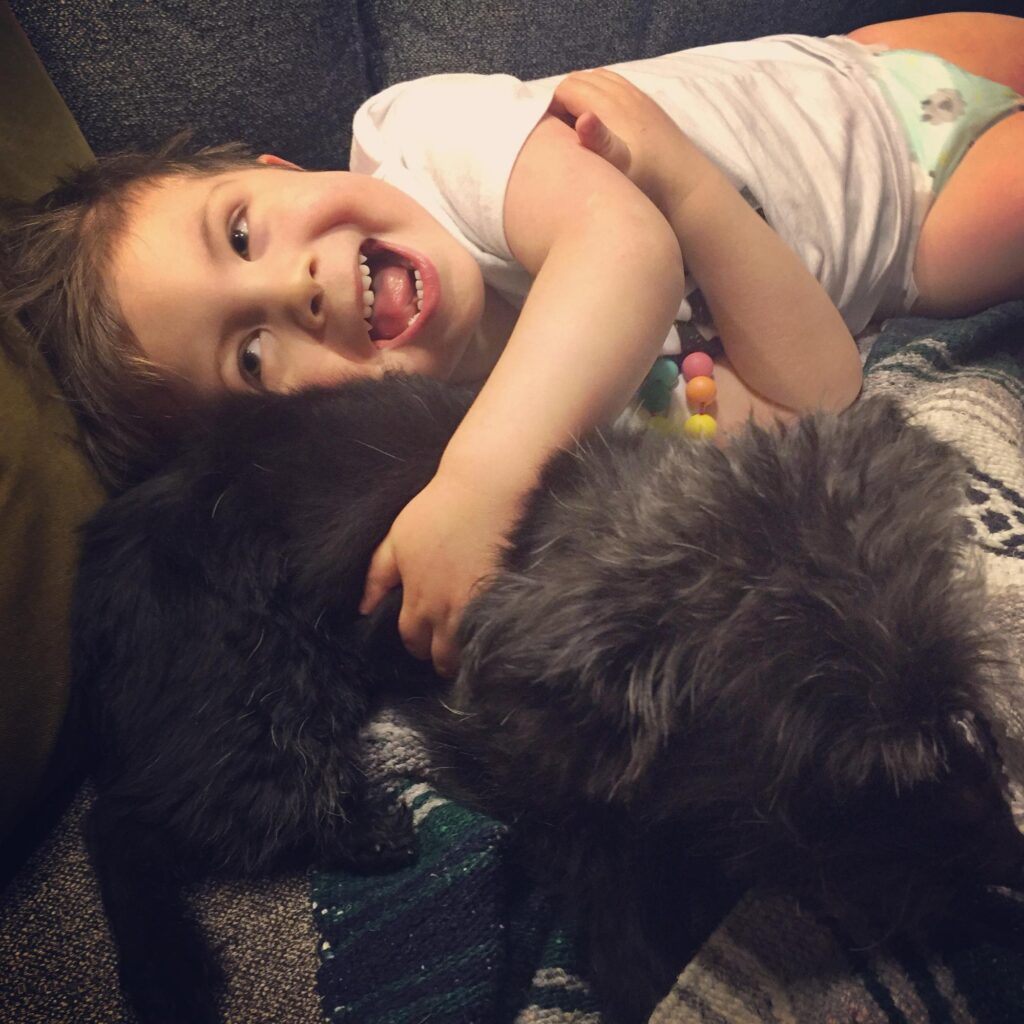 Dean cuddling with his reluctant small yorkipoo dog.