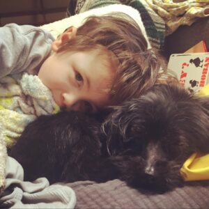 Dean cuddling with his small yorkipoo dog.
